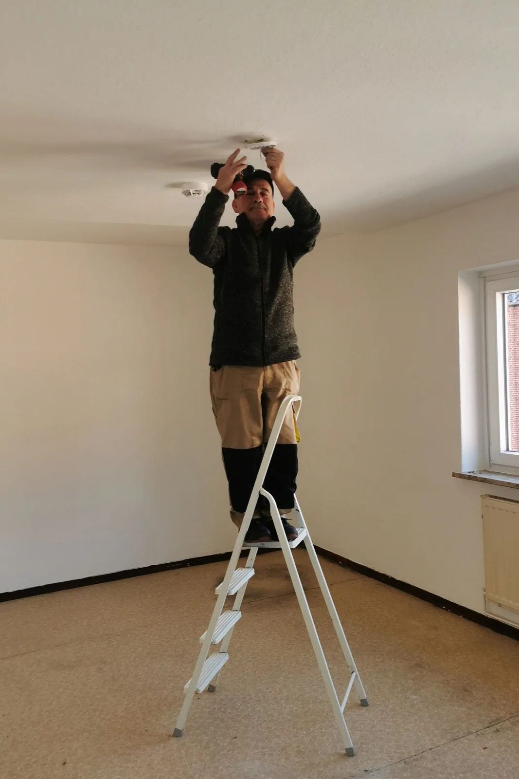 Fitting a ceiling detector from a step ladder, for ceiling fan installation in Buffalo