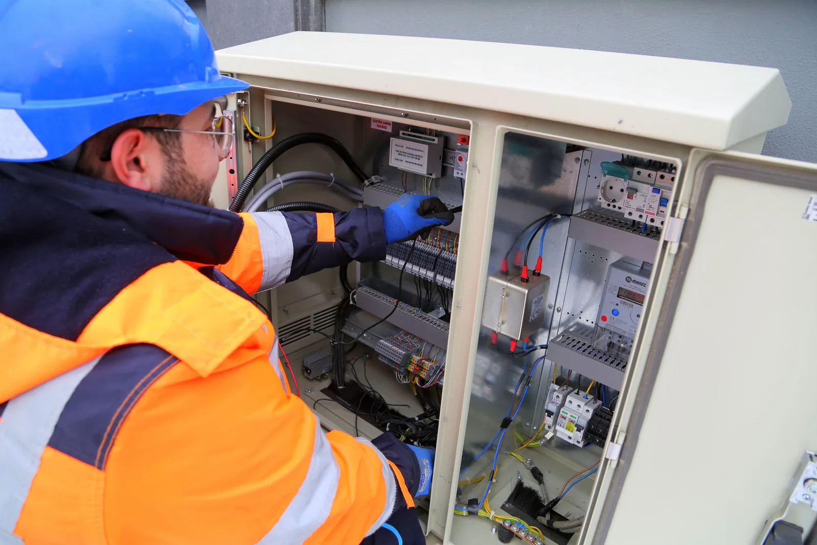 An electrician working in an outdoor service cabinet, for maintenance plans in Buffalo